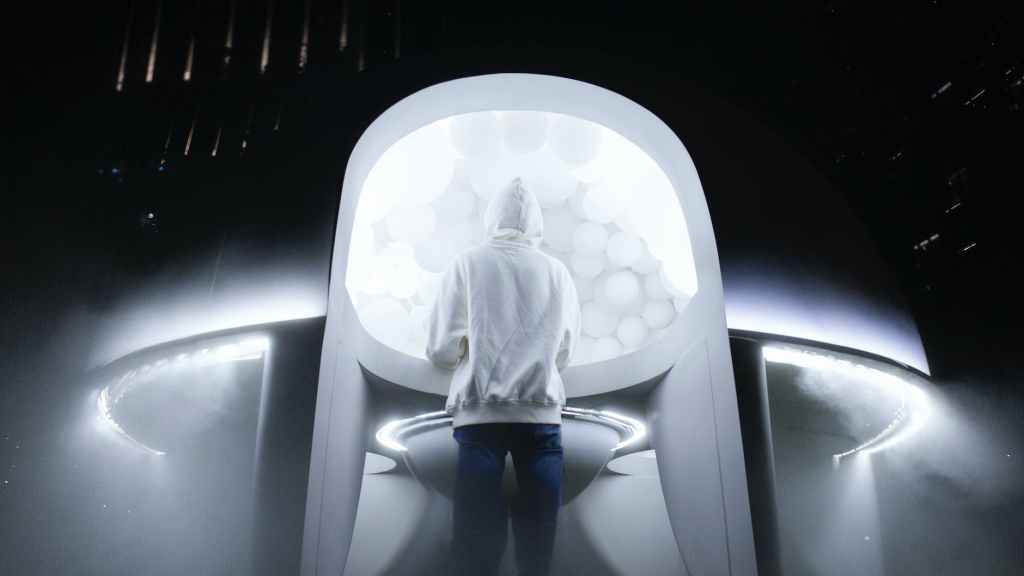 person in white hoodie standing near a ufo