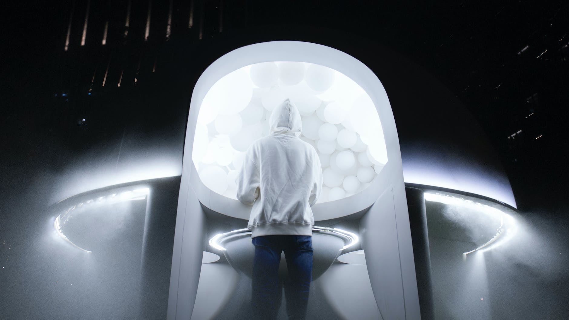 person in white hoodie standing near a ufo
