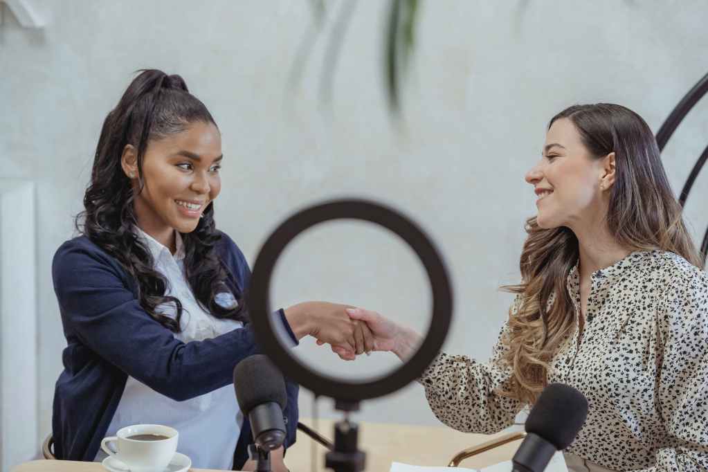 cheerful diverse women shaking hands after interview in studio